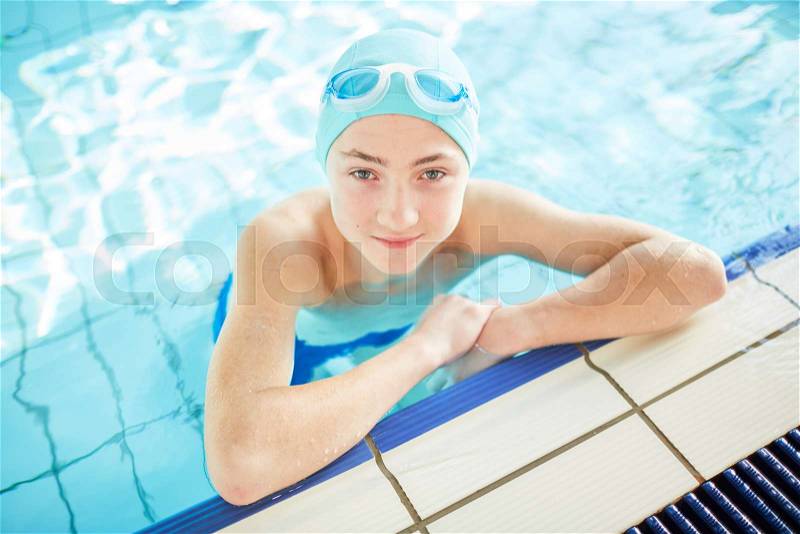Handsome guy in swim-cap looking at camera out of water while practicing swimming, stock photo
