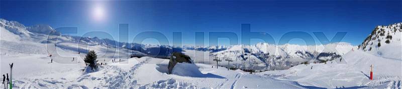 Beautiful panoramic landscape on the slopes in the snowy mountain under sunny blue sky, stock photo
