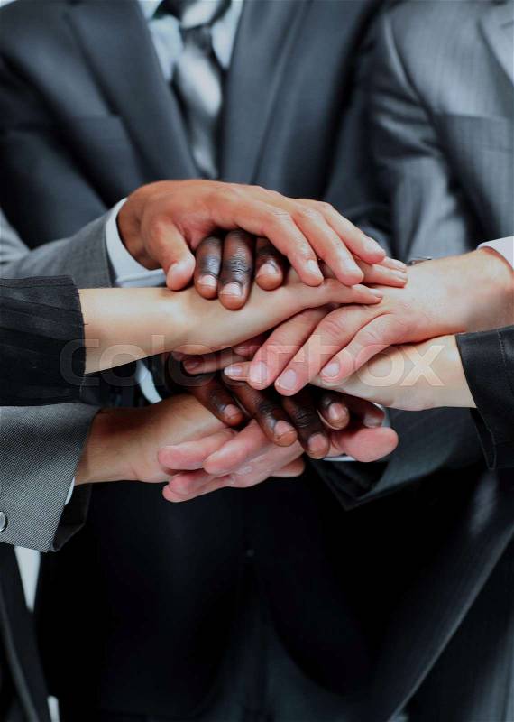A diverse group of workers, hands clasped in the form of teamwork, stock photo