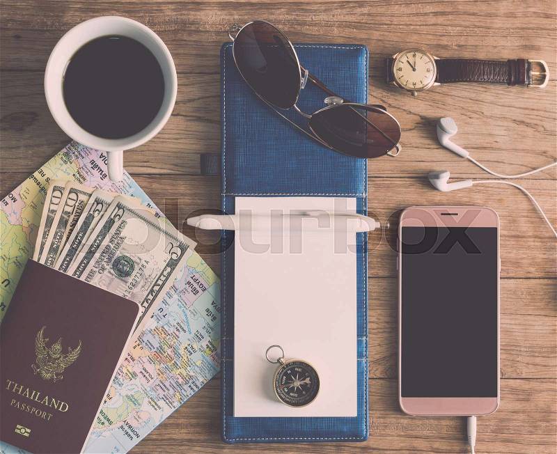 Notebook, Pen, Sunglasses, Coffee Cup, Passport, Money, Mobile Phone, Earphones, Map, wristwatch and Compass on wooden plank. Travel Concept, stock photo