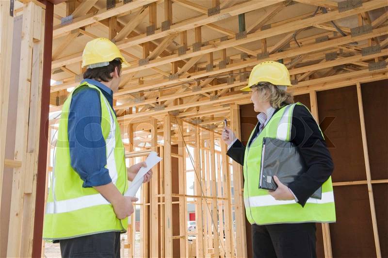 Civil engineer and worker discussing issues at the construction site Focus onthe rear, stock photo