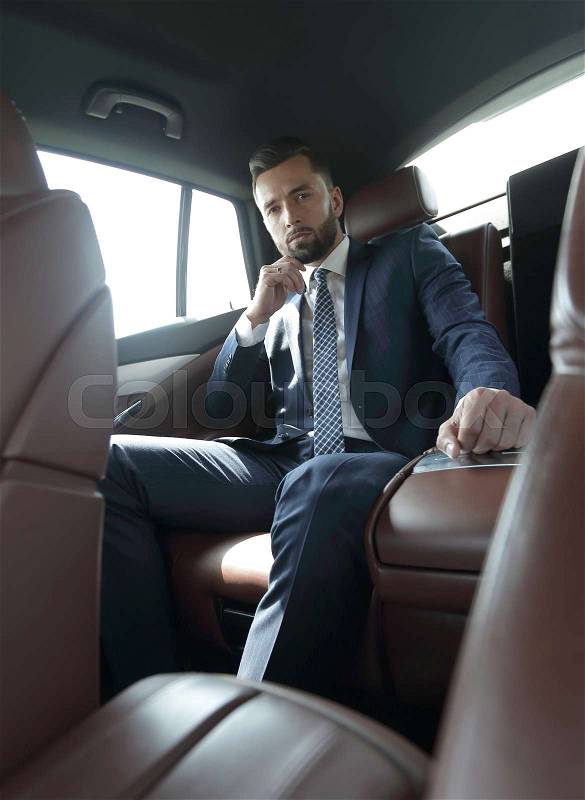 Successful businessman sitting in the back seat of a car, stock photo