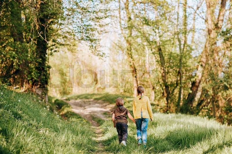 Two funny kids playing together in spring forest, little brother and sister enjoying nice walk in woods, stock photo