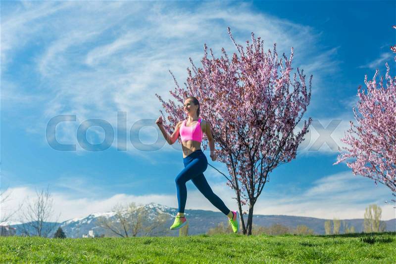 Woman running for fitness run in the spring sun, stock photo