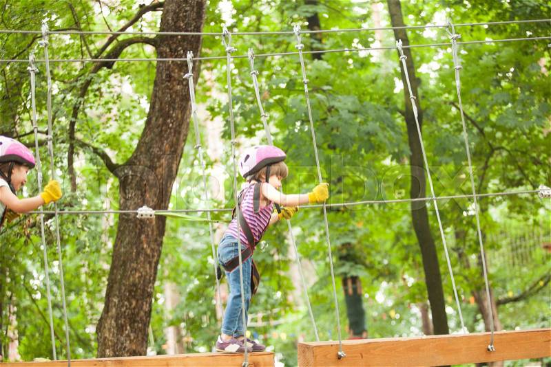 Kids on obstacle course in adventure park in mountain helmet and safety equipment, stock photo