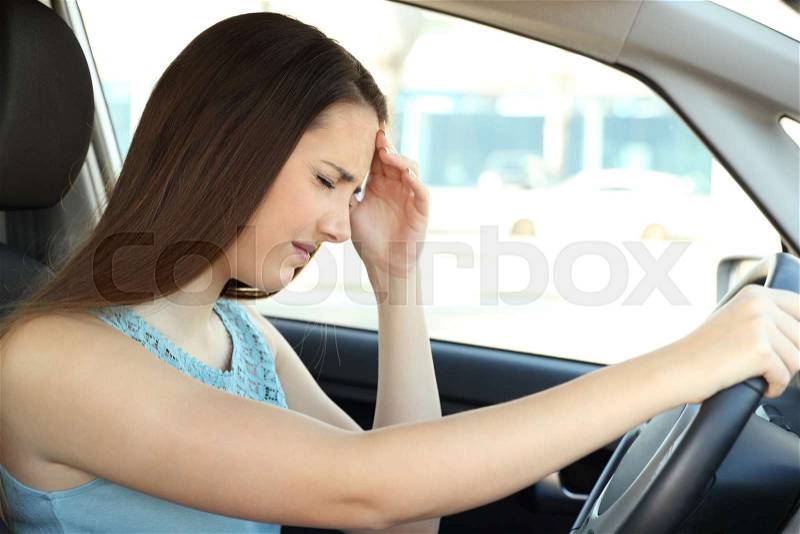 Side view portrait of a driver suffering migraine driving a car, stock photo