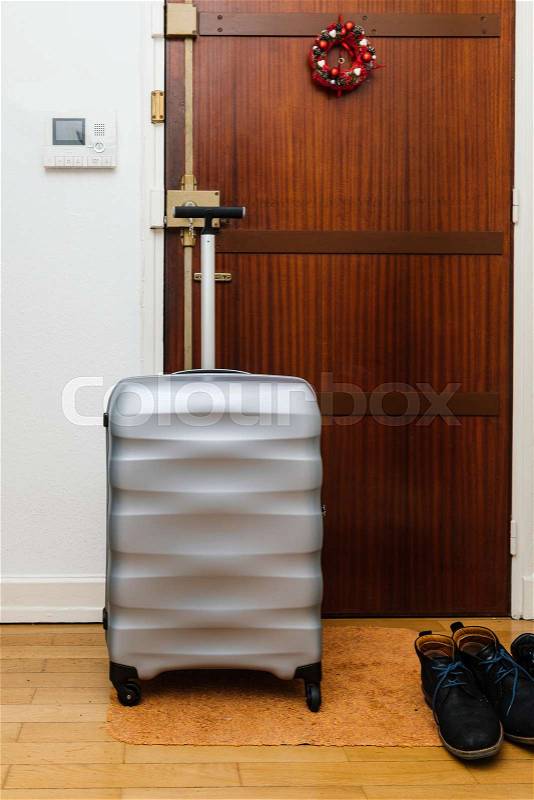 Travel suitcase briefcase luggage in front of the wooden door before departure arrival at homewith Christmas wreath on the door , stock photo