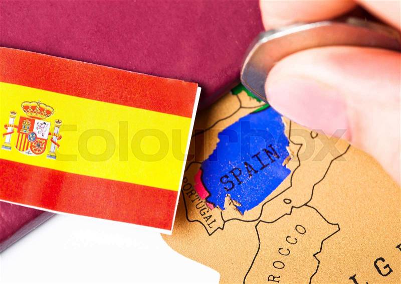 Travel holiday to Spain concept with passport and flag with female hand choosing Spain on the map, stock photo