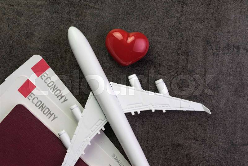 Travel lover, honeymoon trip or valentine\'s gift concept, toy airplane, boarding pass and passport with red and pink heart shape on black texture chalkboard with copy space, stock photo