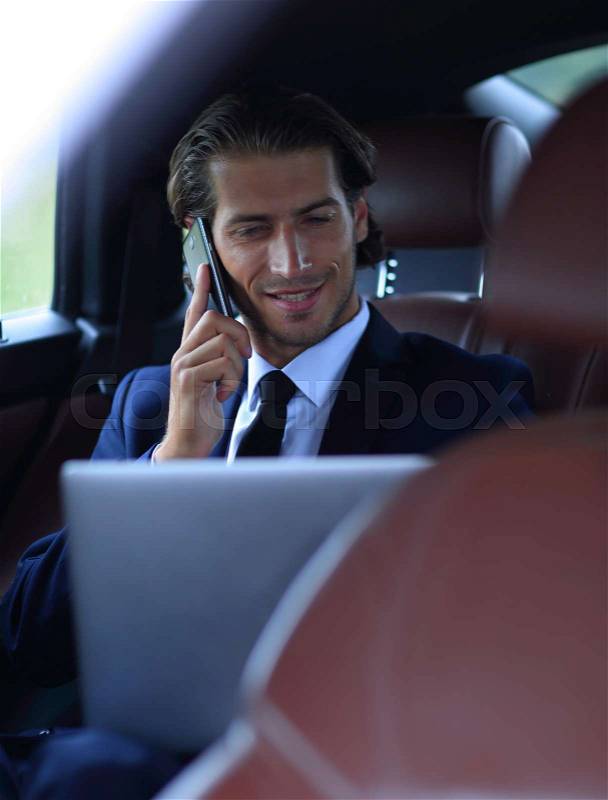 Businessman in his car talking on the smartphone, stock photo