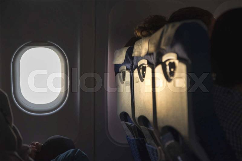 Window seat in airplane cabin when flying at sunset time, stock photo