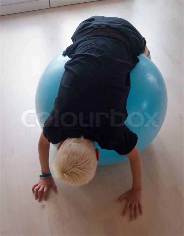 Young teenager is active with the pilates ball in the living room Available light from the door, stock photo