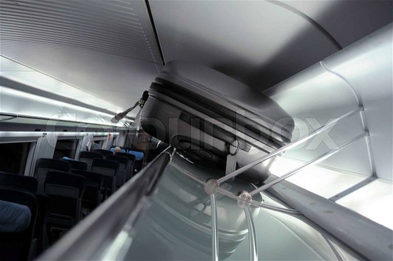 This photograph represent a suitcase on luggage rack in train, stock photo