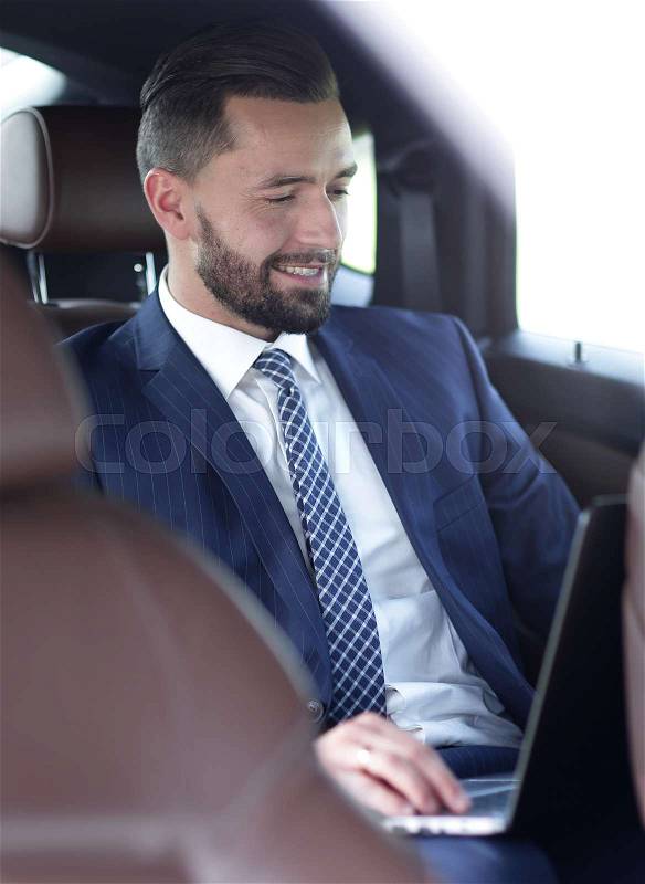 Portrait of a successful business man in the back seat of a car, stock photo