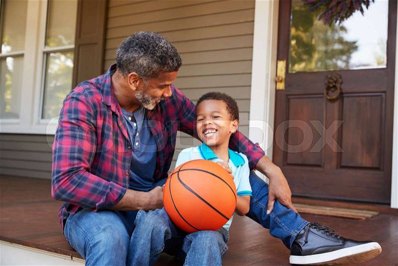 Father And Son Discussing Basketball On Porch Of Home, stock photo
