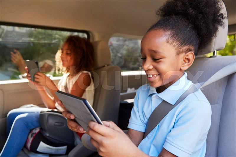 Children Using Digital Devices On Car Journey, stock photo