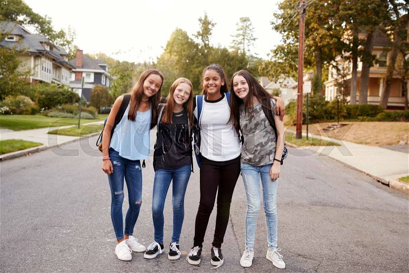 Teen girls on the way to school look to camera, full length, stock photo