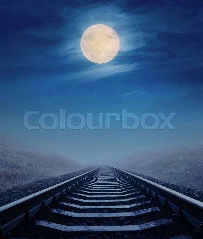 Full moon in clouds over railroad to horizon. Mystery halloween concept, stock photo