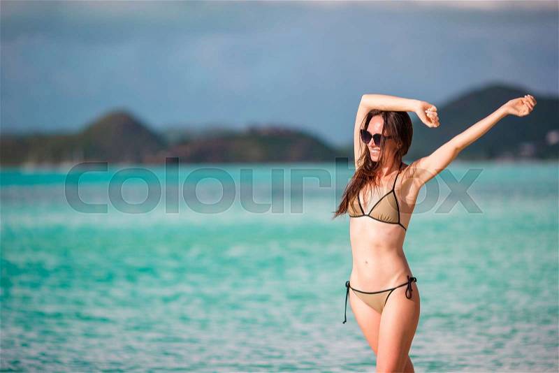 Beach vacation people - woman looking at perfect paradise with turquoise ocean water on caribbean vacation. Girl in bikini sunbathing on travel holidays on luxury island, stock photo