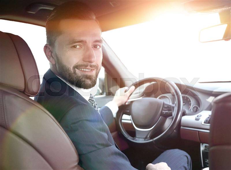Confident businessman sitting at the wheel of a prestigious car, stock photo