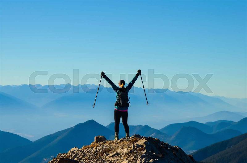 Woman celebrating reaching a mountain summit whiler hiking, stock photo
