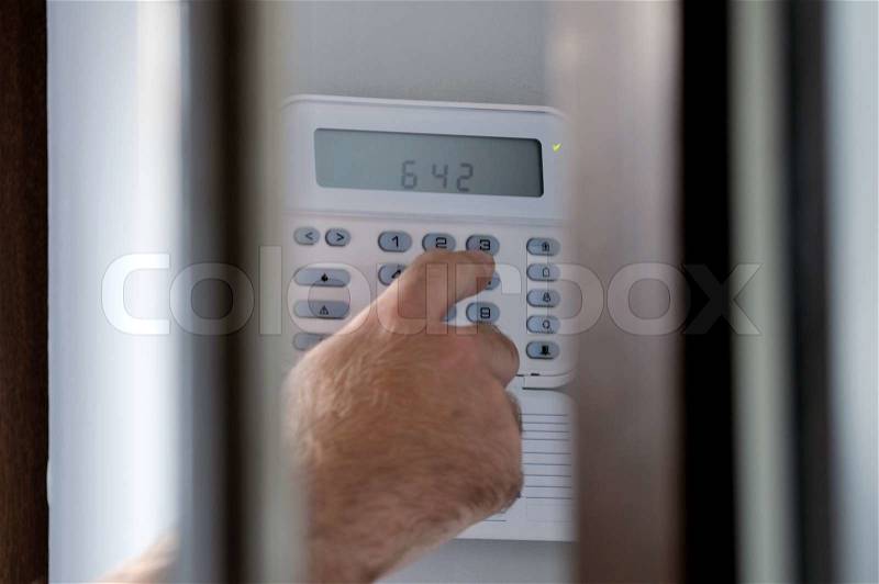 Human hand arming a burglar alarm system The view is similar as a a spy view this situation, stock photo