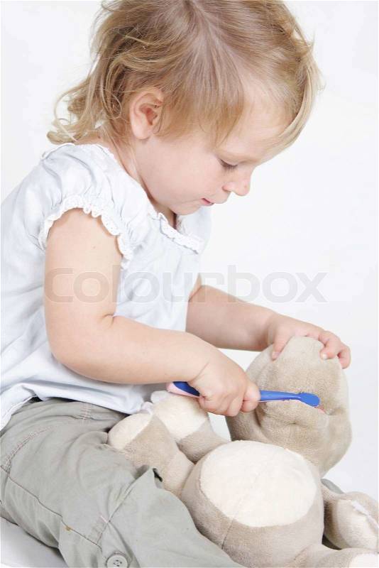 Cute child cleaning teeth to no-name toy hippo, stock photo