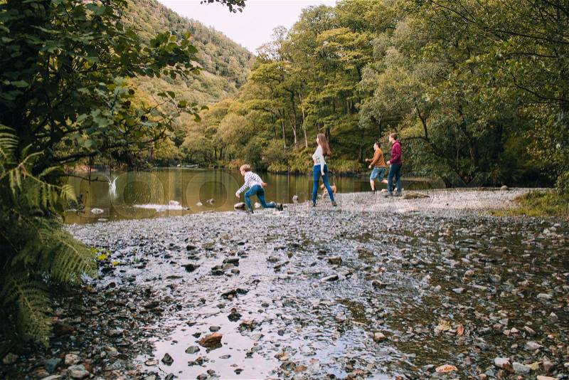 Family are skimming stones on a lake in the Lake District, stock photo