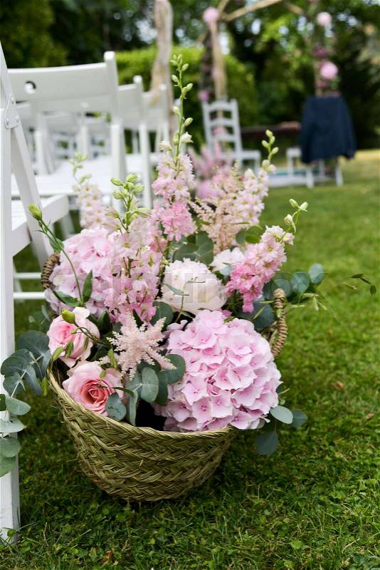 Closeup of an arrangement of different pale pink flowers in a basket, as a decoration in an open-air wedding ceremony, stock photo