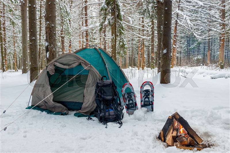 Closed tent in the snow in the winter forest and a fire, no people, stock photo