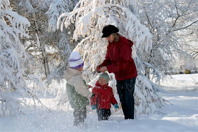 Happy family mother with small boy and girl in winter snow covered city park, stock photo