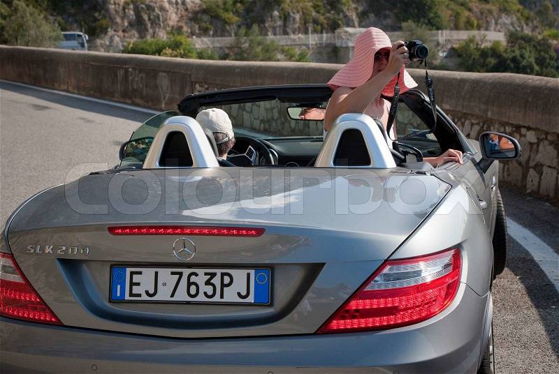 SIGHTSEEING FROM THE CAR, AMALFI, ITALY - SEPTEMBER 24, 2011: A well-to-do female tourist making snapshots along the coast road of Amalfi, Italy without leaving the car, stock photo