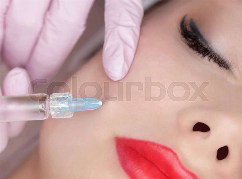 The doctor cosmetologist makes the Rejuvenating facial injections procedure for tightening and smoothing wrinkles on the face skin of a beautiful woman in a beauty ..., stock photo