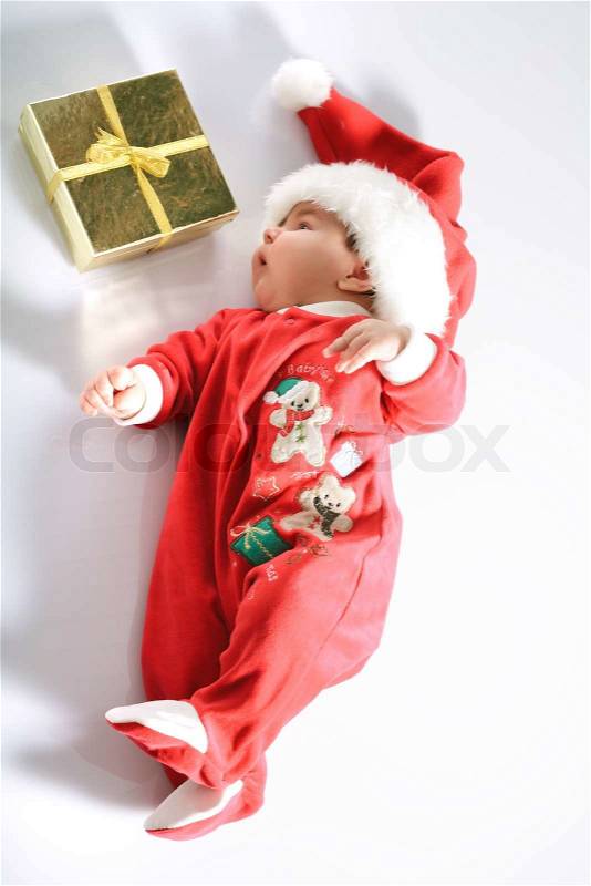 Cute baby in santa wear and gold gift on white, stock photo