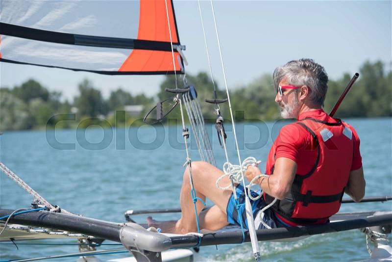 Sailing man on sailboat during competition, stock photo