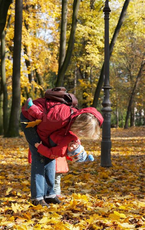 Happy family mother with small children in golden autumn city park, stock photo