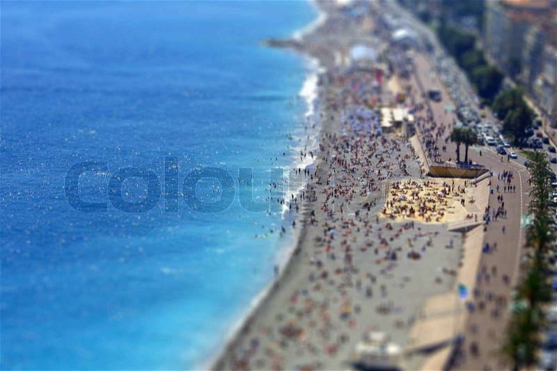 Tilt-shift miniature effect of aerial view of crowded Mediterranean beach in City of Nice, France, stock photo