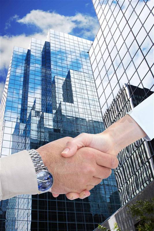 Business handshake and skyscrapers. To complete an agreement, stock photo