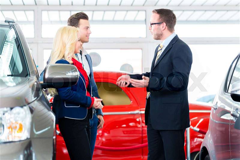 Couple buying car at dealership and consulting salesman, stock photo