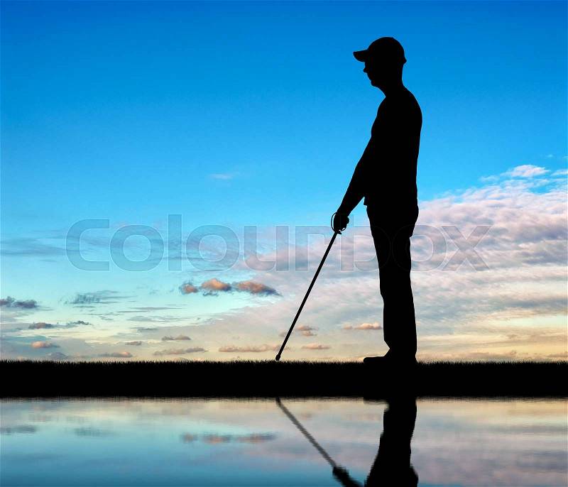 Silhouette of a blind man with a cane in his hand, stands by the river with his reflection. The concept of blind people with disabilities, stock photo