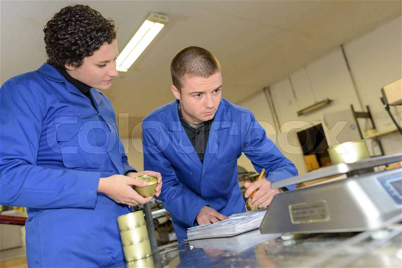 Worker noting weight of tin can, stock photo