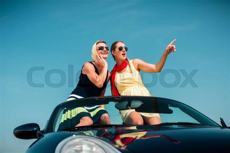 Woman having summer trip in convertible car stretching hands in the air with fun, stock photo