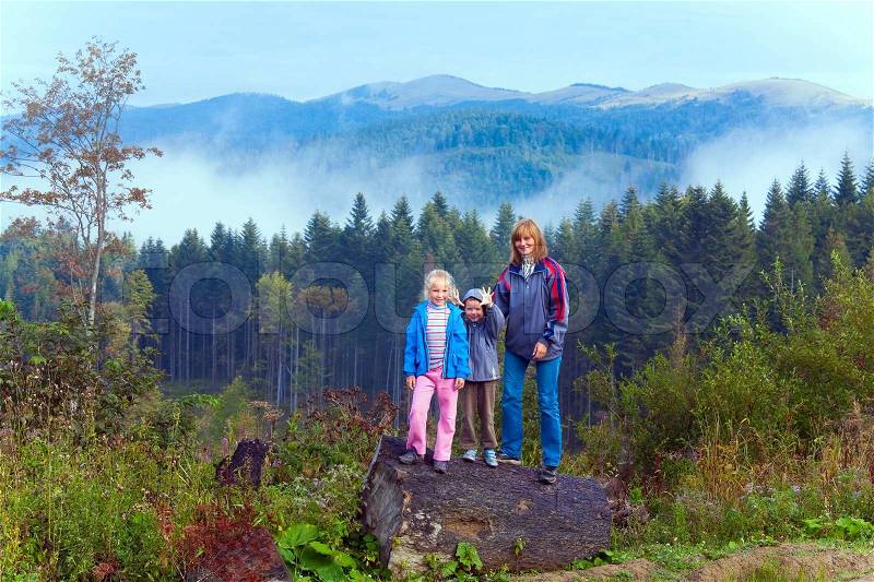 Family on september Carpathian mountain hill and cloudy morning view behind, stock photo