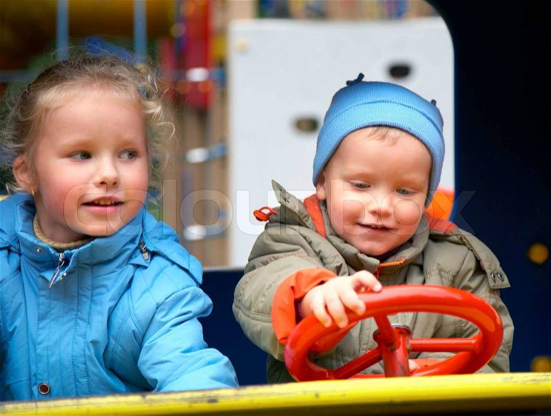 Little boy is learning to drive on the pleasure-ground and his sister, stock photo