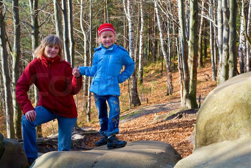 Family on walk in the autumn forest with large stone, stock photo