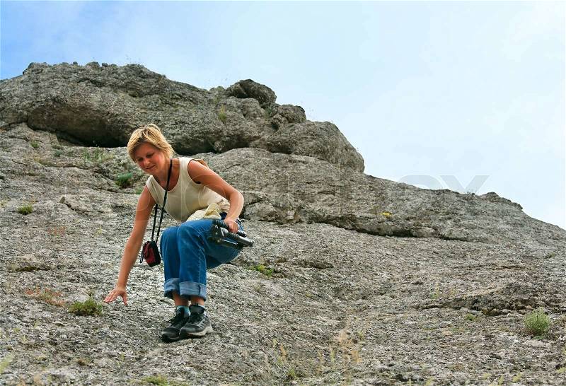 Woman with camera and tripod on rocky hill, stock photo