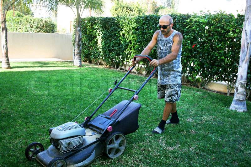 Gardener by work mowing the lawn, stock photo
