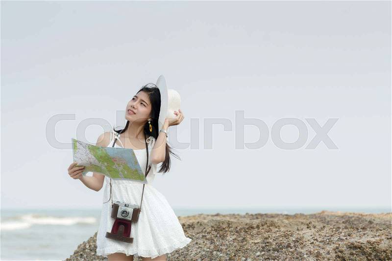 Happy tourist woman holding map on the beach, stock photo