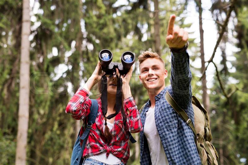 Teenage couple with binoculars hiking in forest. Summer vacation adventure, stock photo