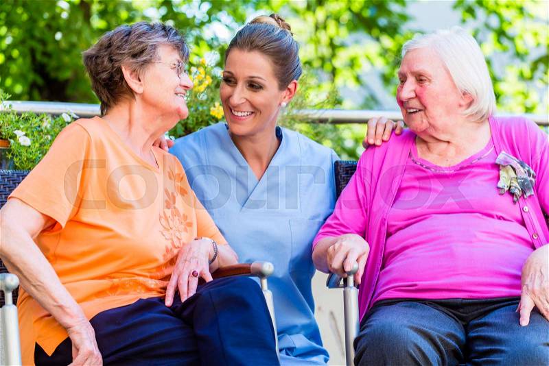 Geriatric nurse having chat with senior women in retirement home, stock photo